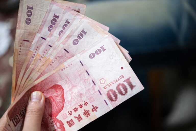 手に持たれた複数枚の100台湾ドル紙幣。台湾の通貨を使う場面や両替、物価に関する文脈に最適なイメージ。