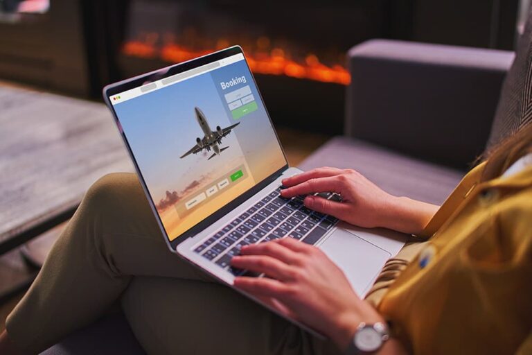 ノートパソコンで航空券の予約サイトを操作し、旅行を予約する手元