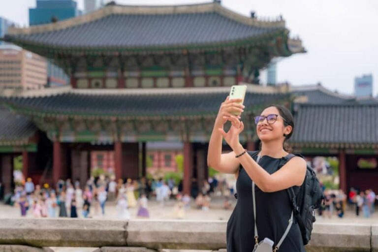 ソウルの宮殿前でスマホを使って写真を撮る旅行者