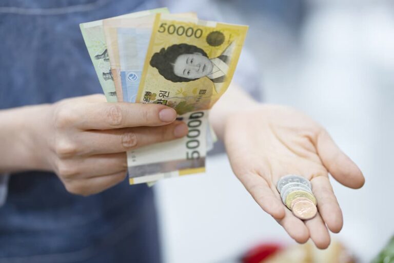 韓国ウォンの紙幣と硬貨を手のひらに広げた様子