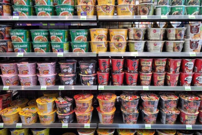 韓国のコンビニに並ぶカップラーメンの棚。辛ラーメンやプルダック麺、チーズラーメンなど多種多様なインスタント麺が整然と陳列されている。