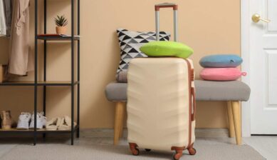 玄関に置かれたスーツケースとネックピローのある旅行準備の様子