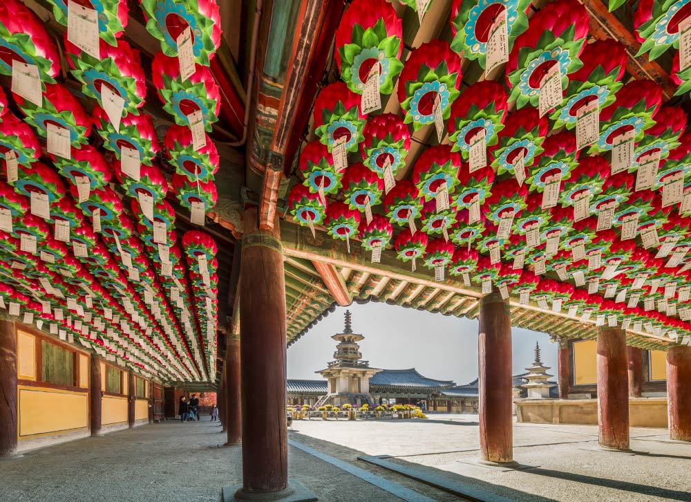 韓国・慶州の仏国寺の回廊に飾られた蓮の形をした赤い提灯。願い事が書かれた紙が吊るされ、寺院の荘厳な雰囲気を引き立てている。