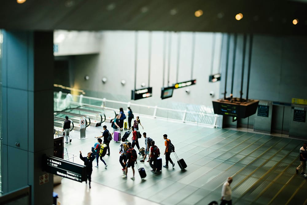 イタリアの空港で入国審査に向かう旅行者たちの写真