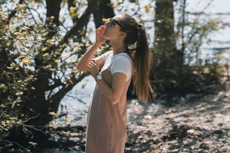 秋のイタリアの公園で茶色いワンピースを着た女性が植物を眺めている写真