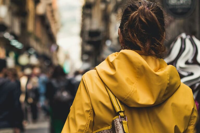 春用の黄色いジャケットを着た女性がイタリアの街を歩いている写真