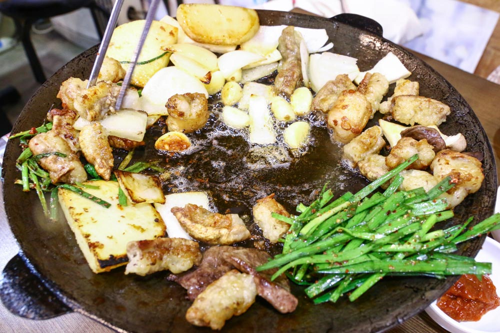 韓国の人気グルメ「コプチャン焼き」。牛や豚のホルモンを鉄板で香ばしく焼き上げ、ニンニクやニラ、ジャガイモと一緒に楽しむ。