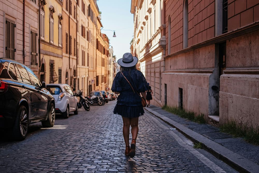 イタリアの街並みを日陰から歩く女性の写真