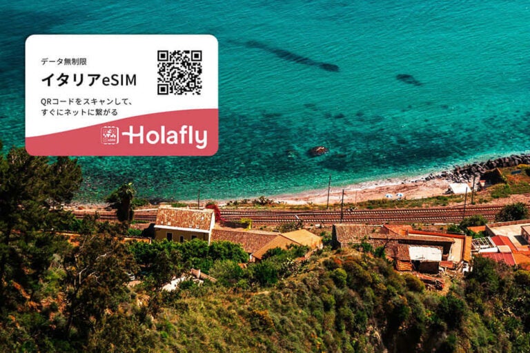 イタリアの美しい海と民家の写真。左上にHolaflyイタリアeSIMのQRコード。