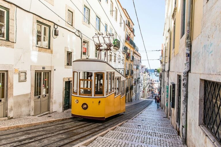 ポルトガル・リスボンの坂道を走る名物の黄色い路面電車と石畳の街並み