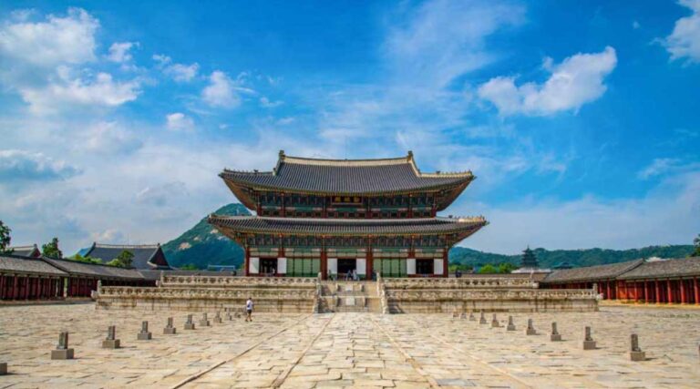 韓国・ソウルにある景福宮（キョンボックン）の勤政殿（クンジョンジョン）。広大な石畳の中庭と歴史ある宮殿建築が、青空の下で堂々とした姿を見せている。