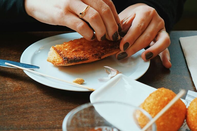 レストランでバゲットをちぎっている女性の手元の写真