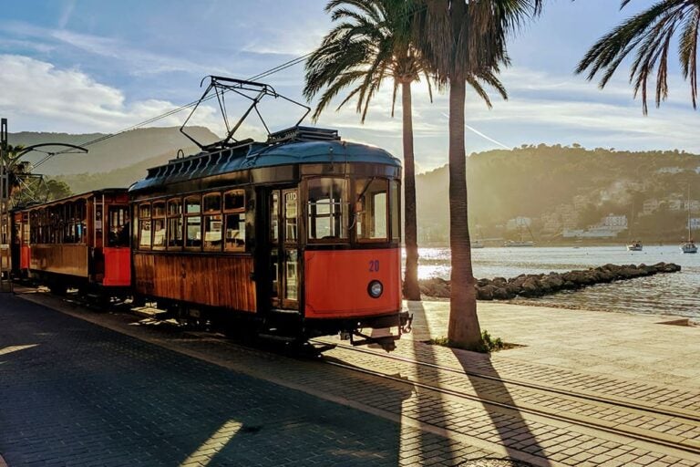 スペインの海辺の街を走るオレンジ色のトラムの写真