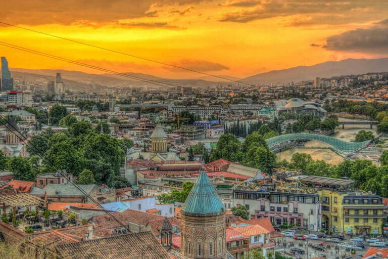 ジョージア・トビリシ旧市街の街並みと夕焼け空を見渡す風景写真。伝統建築と現代都市が融合した人気観光地の景観を紹介