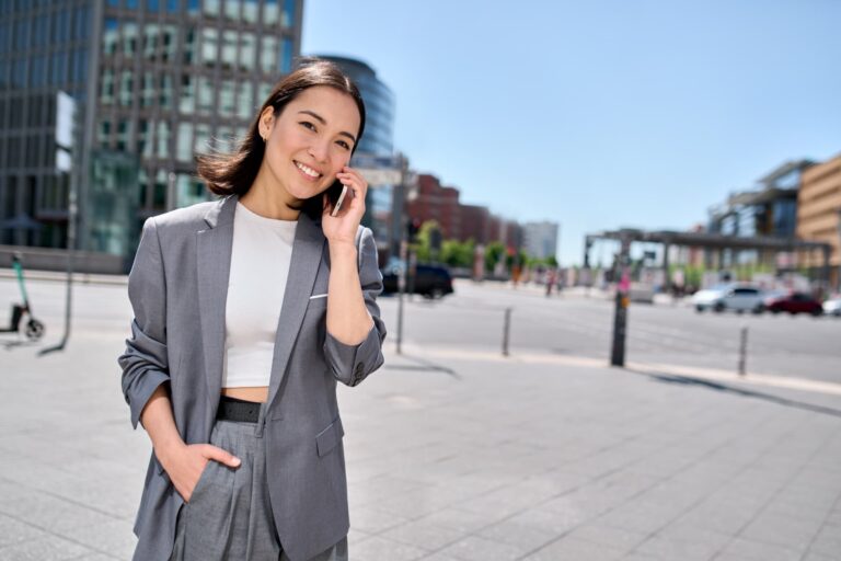 海外の街中でスマートフォンを使い、eSIMで音声通話する女性