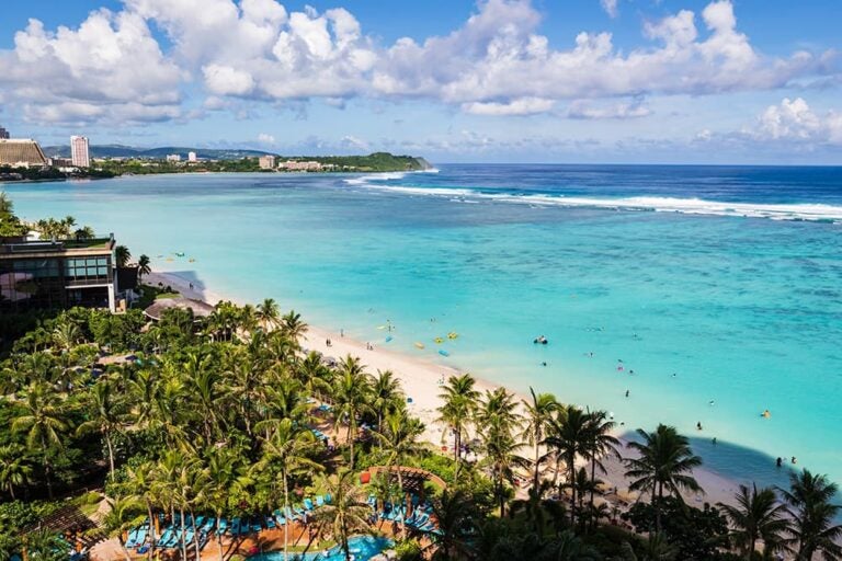 グアム・タモン湾の遠浅のビーチとリゾートホテル沿いに広がるヤシ並木の眺望