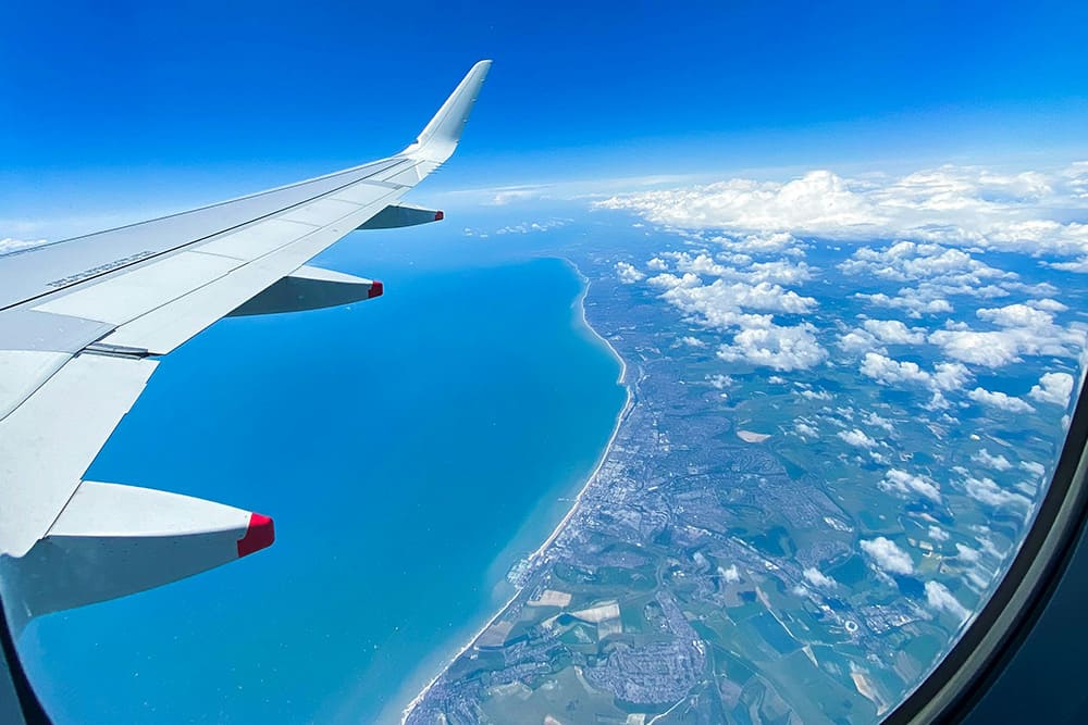 飛行機の窓から見下ろす海岸線の風景。7月の海外旅行に出発する際の空