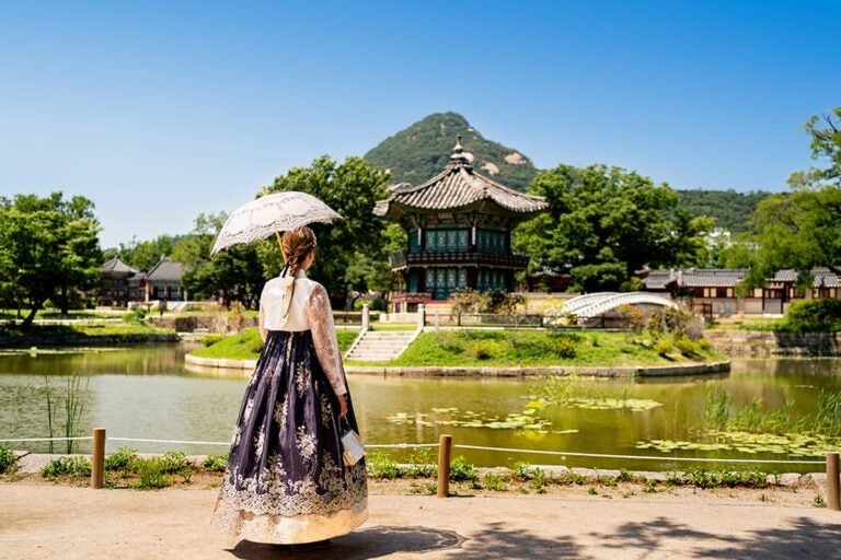 景福宮の香遠亭を背景に韓服姿で日傘をさす女性の後ろ姿