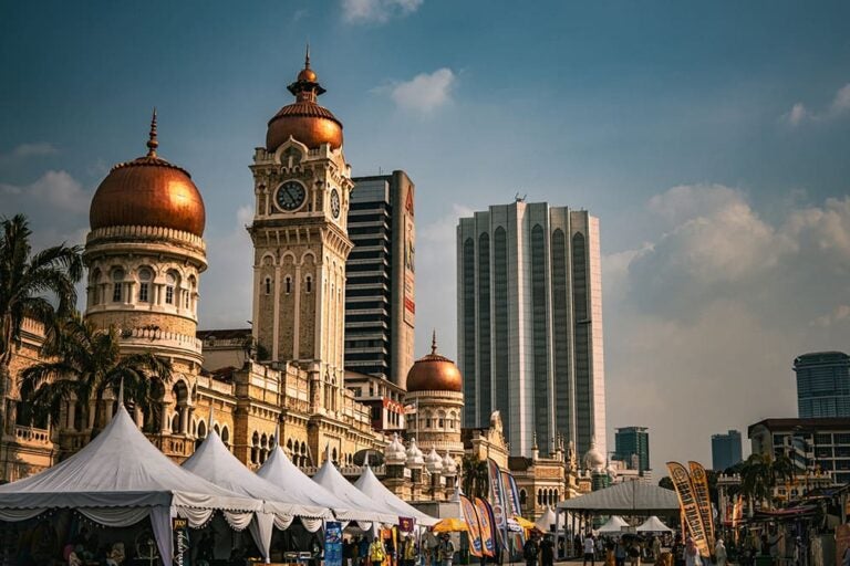 マレーシア・クアラルンプールのスルタン・アブドゥル・サマドビルと市街地のにぎわいを表している。