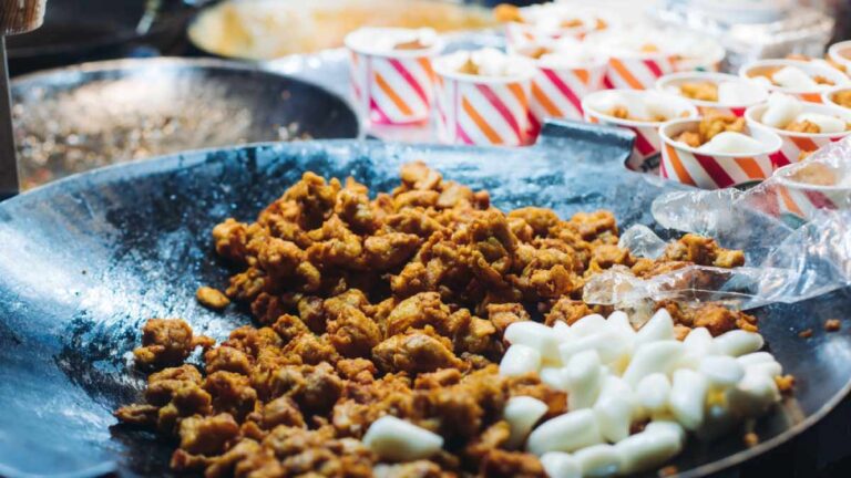 韓国・大邱の屋台で提供されるストリートフード。大きな鉄板に並ぶカリカリのヤンニョムチキンと白いトッポッキ(餅)が食欲をそそる。