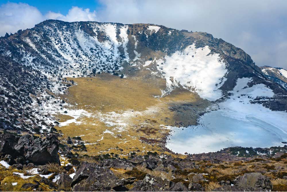 雪が残る冬の漢拏山(ハルラサン)の火口。済州島の象徴とも言える壮大な自然風景が広がる。