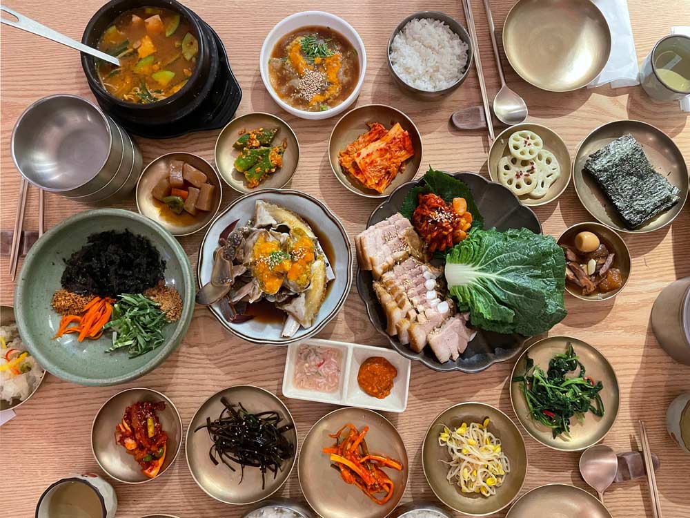 韓国の伝統料理「韓食(ハンシク)」の豊かな食卓。ポッサム、ケジャン、ナムル、キムチ、テンジャンチゲなど多彩なおかずが並ぶ豪華な韓国料理のフルコース。