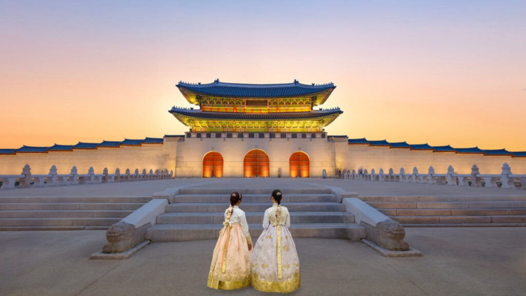 韓国・ソウルの景福宮の正門「光化門」を背景に、韓服を着た女性たちが夕暮れの広場に立つ幻想的な光景。