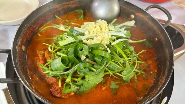 韓国の代表的な鍋料理メウンタン。赤く煮えたぎるスープの中に魚とたっぷりのニラや香味野菜、刻みニンニクが乗せられた食欲をそそる一品。