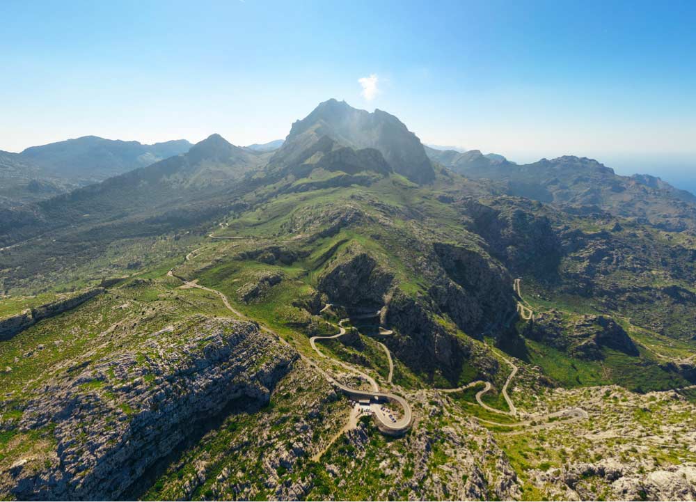スペイン・マヨルカ島の世界遺産、トラムンタナ山脈を走るくねくねとした山道の空撮写真。壮大な山岳風景と自然の美しさが広がる絶景ルート。
