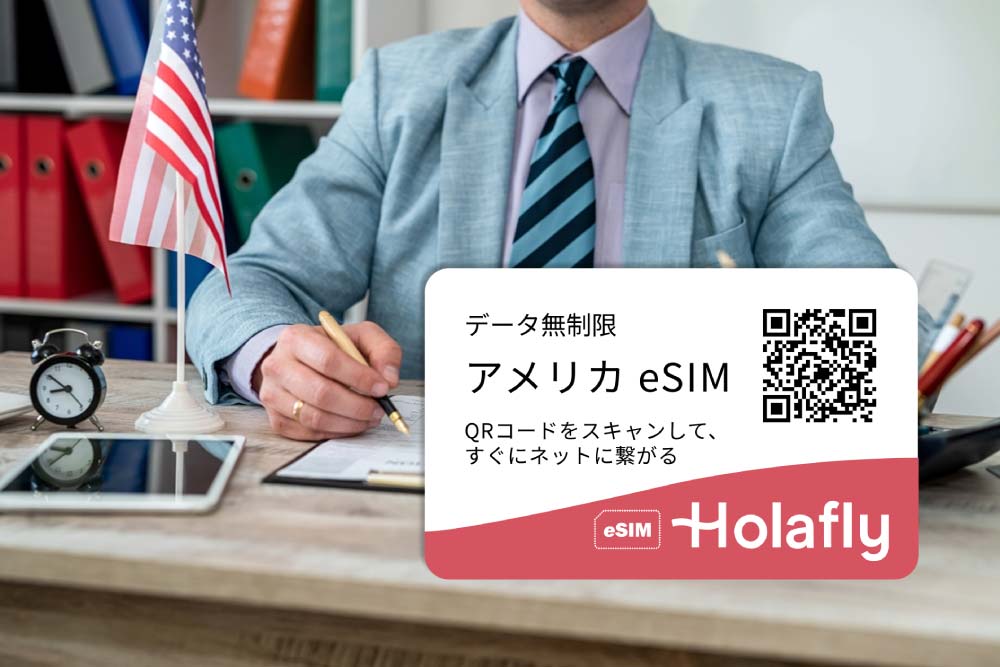 アメリカ国旗とビザ申請書類が置かれたデスクの上に、Holaflyの「アメリカ eSIM」広告バナーが重ねられた画像。