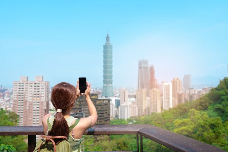台北101を背景にスマートフォンで撮影する旅行者