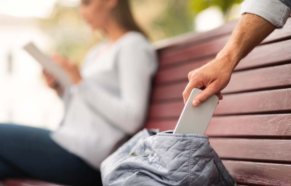 オーストラリア旅行中にベンチでスマホに集中する女性の隙を狙ってバッグからスマートフォンを抜き取る犯人の手元。