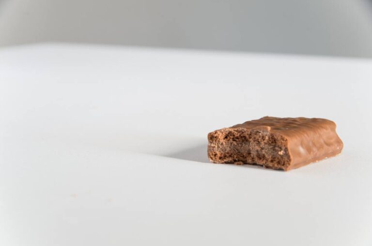 ひとかじりされたチョコレートバーが白い背景の上に置かれている。中のチョコレートクリームやビスケット層が見えている。