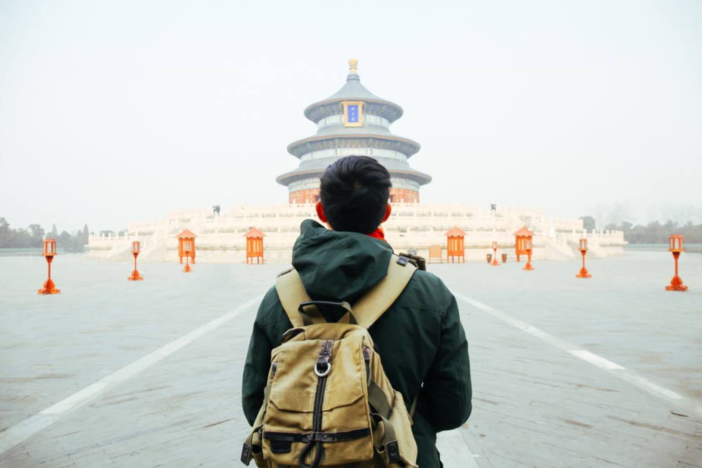 中国・北京の天壇を訪れるバックパックを背負った旅行者の後ろ姿。歴史ある観光名所を観光する様子。