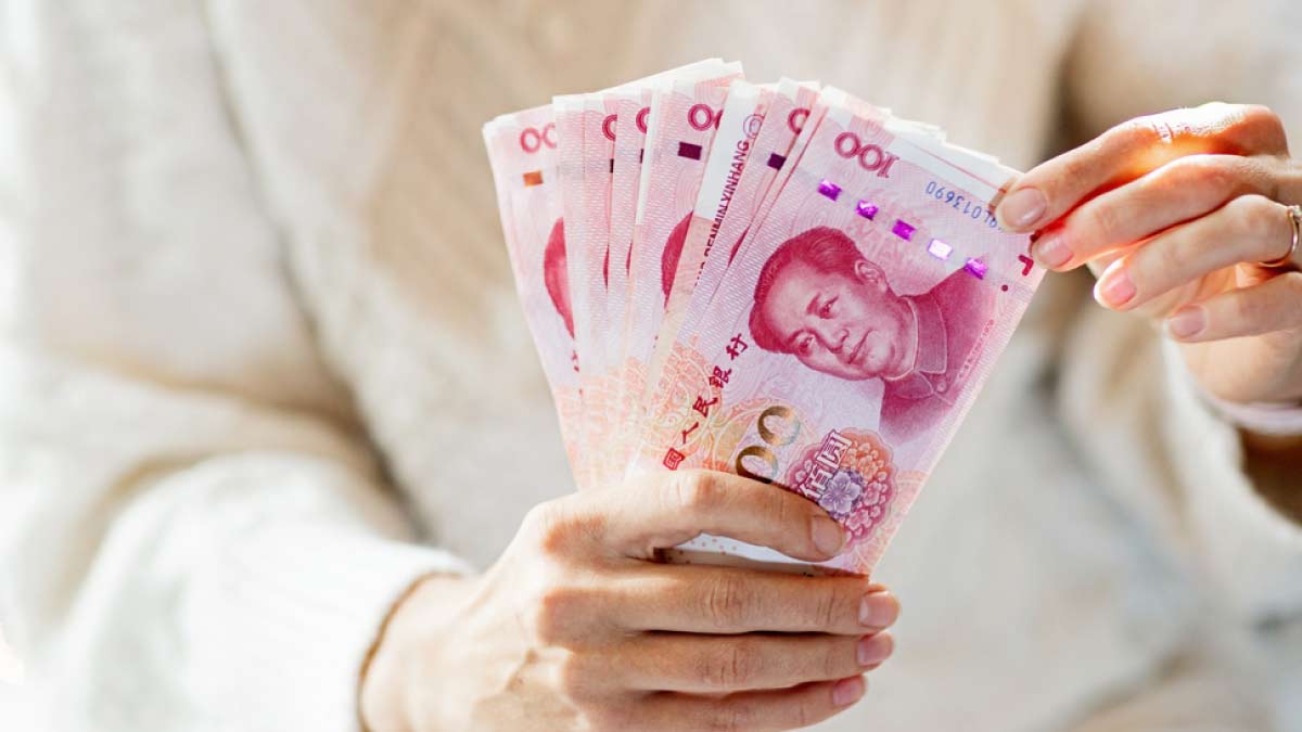 100元札の中国紙幣を扇状に広げて持つ人の手元。