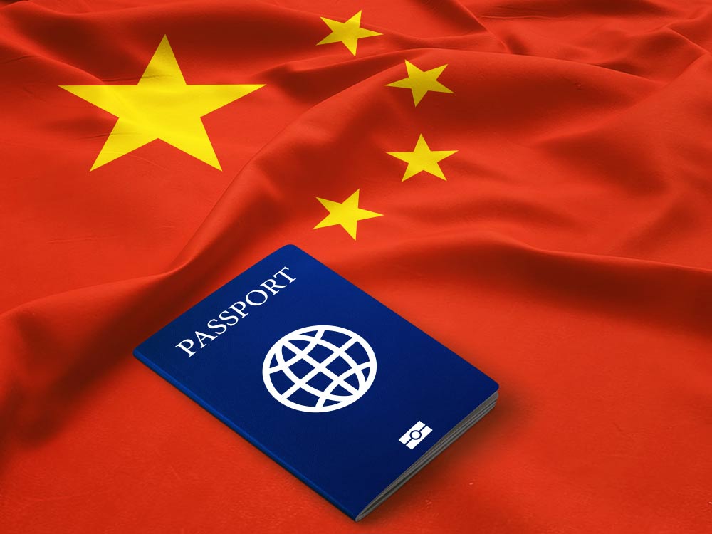 中国国旗の上に置かれた青いパスポート。中国への渡航やビザ申請を連想させるイメージ。