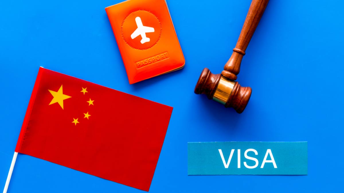 中国国旗、ビザ、パスポート、判子(ガベル)が青い背景に並べられた、中国ビザや入国審査をイメージしたコンセプト画像。