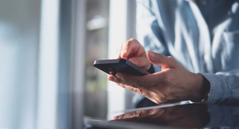 スマートフォンを操作する手元のクローズアップ。室内でアプリやインターネットを利用している様子。