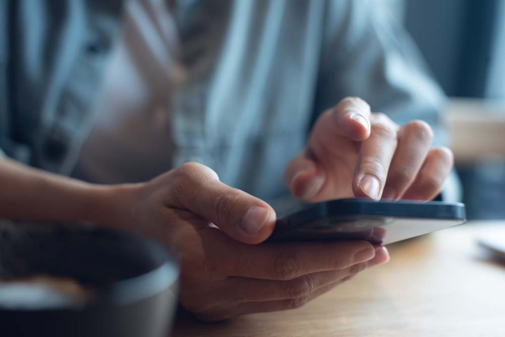 スマートフォンで連絡先を確認・入力する手元のクローズアップ。
