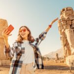 ルクソールのメムノンの巨像前で記念撮影をする女性観光客。