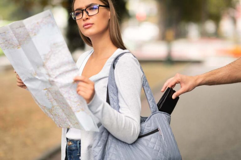 旅行中の女性が地図を見ている隙にバッグから財布を抜き取られる様子。