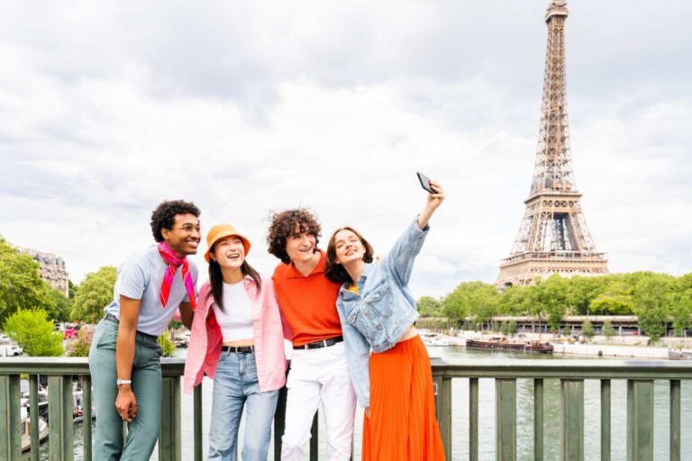 エッフェル塔を背景に橋の上で記念写真を撮る観光客グループ。