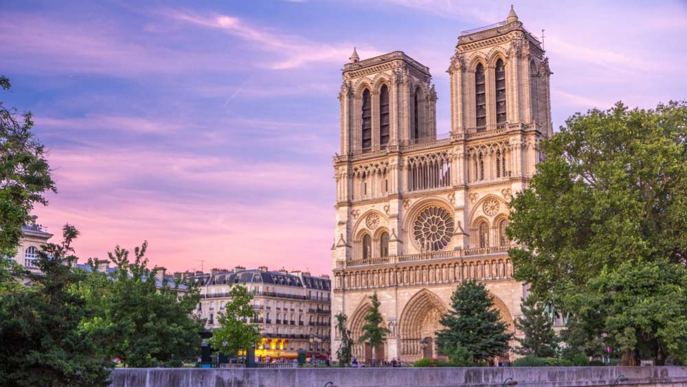 フランス・パリのノートルダム大聖堂を夕暮れ時に撮影した風景。柔らかな夕焼け空と歴史的建造物が美しく調和している