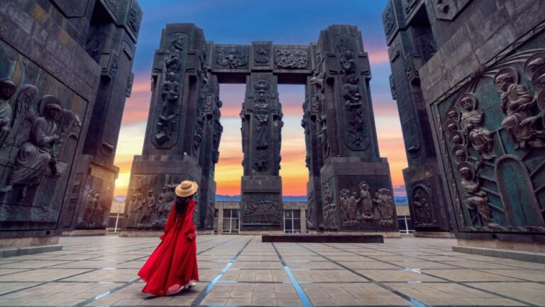 ジョージア・トビリシの観光名所「ジョージア年代記の記念碑」を、夕焼けの中で見上げる旅行者の後ろ姿