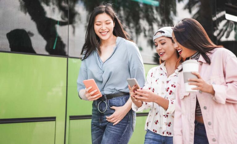 週末旅行中の3人の女性が街歩きしながらスマートフォンで旅のプランを確認している様子