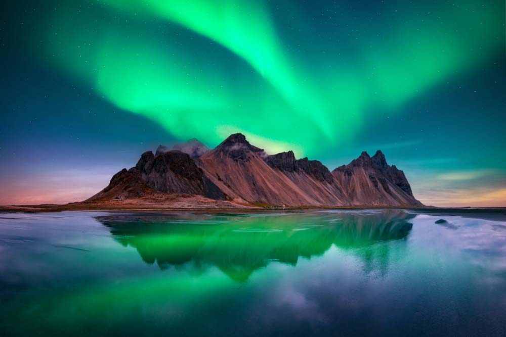 アイスランドのヴェストラホーン山と湖面に映るオーロラ、幻想的な夜空が広がる絶景