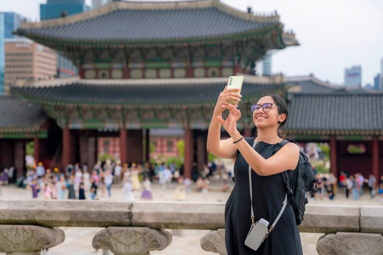 ソウルの景福宮（キョンボックン）前でスマートフォンを掲げて写真を撮影する女性観光客