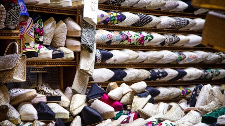 モロッコのスークに並ぶ刺繍入りの伝統的な革靴バブーシュが棚いっぱいに陳列されている様子。