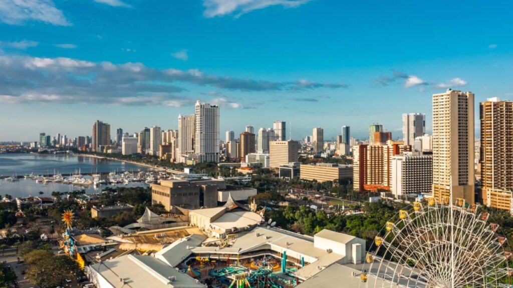 2025年現在のフィリピン・マニラ湾沿いの市街地と観覧車を含むベイエリアの風景。