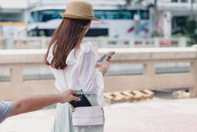 スマートフォンに気を取られた女性旅行者のショルダーバッグから財布を抜き取るスリの瞬間を捉えたシンガポール市内の路上シーン